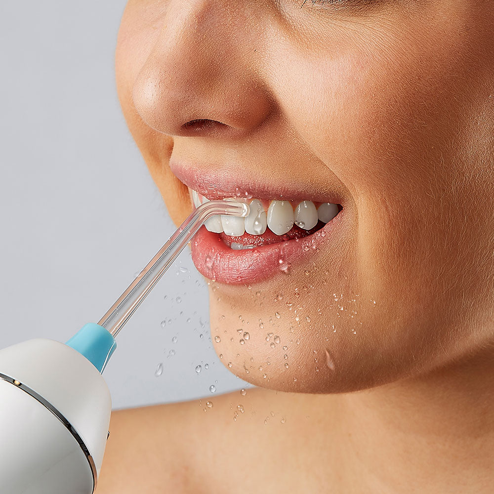 Water flossing food and bacteria from teeth and gums. Blue accessory tip.