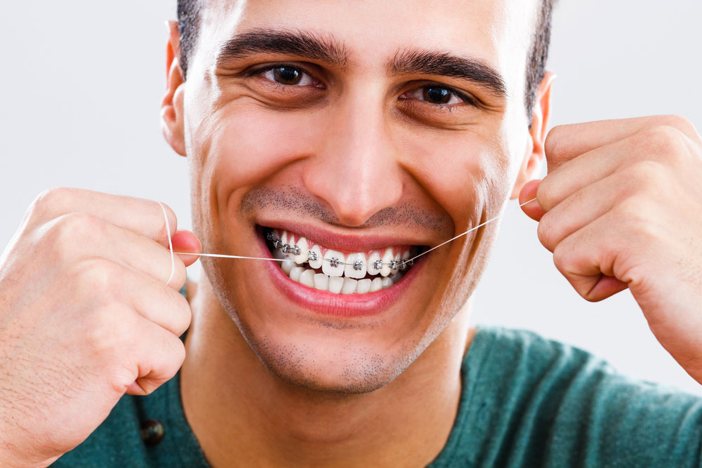 Man using dental floss on braces.